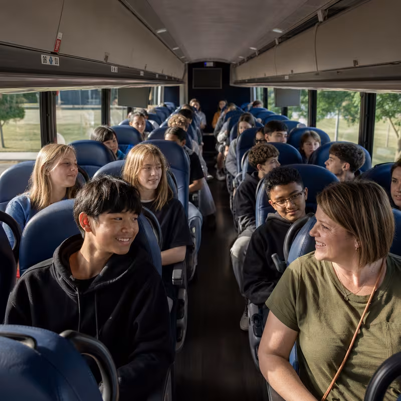Group boarding a white charter bus for School Transportation transportation in Salinas