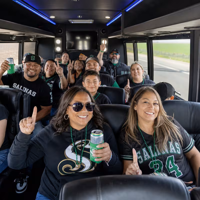 Group boarding a white charter bus for Sporting Event Transportation transportation in Salinas